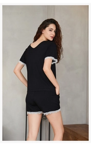 Detail view of black Modal pajamas set featuring white lace trim on sleeves and hem