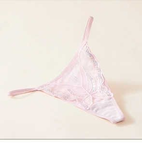 Détail du string en dentelle rose avec broderie papillon et paillettes argentées brillantes