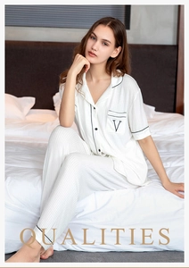 Detail of white modal pajama top with black piping and embroidered V on chest pocket