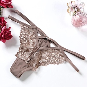 Nude lace thong with floral embroidery and crisscross straps on white background