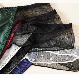 Détail d'un string en satin et dentelle à pois avec coutures fines et textures variées