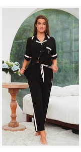 Détail d'un pyjama en modal avec passepoil rose et broderie V sur un tissu noir