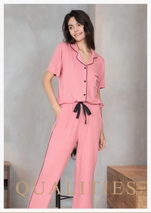Détail d'un pyjama rayé rose avec bordure noire, poche cœur et cordon de serrage en ruban