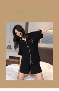 Detail of black short sleeve pajama set with white heart embroidery on pocket and contrast piping