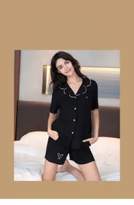 Détail de pyjama noir en modal avec bords roses à volants et imprimé cœur sur le haut
