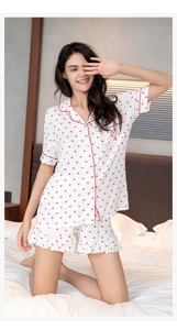 Detail of red heart prints and ruffle hem on a modal pajama set with contrast piping