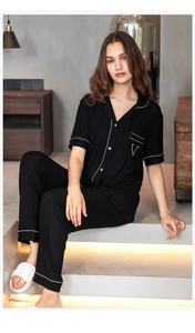 Detail of black striped pajama set featuring pink contrast piping and V letter embroidery