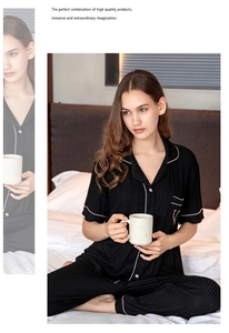 Detail of black striped modal pajama set featuring contrast piping and chest embroidery