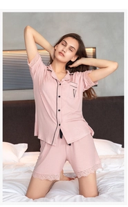 Close-up of pink modal pajamas featuring black piping, letter embroidery, and lace trim