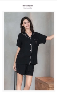 Detail shot of black ribbed modal pajama top showing white piping and heart pocket embroidery