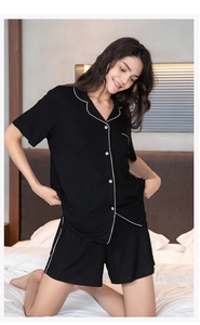 Detail of black ribbed knit pajamas set with contrast white piping and button closure