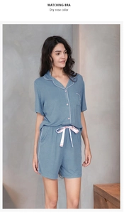 Detail of blue rib-knit pajamas featuring pink piping and a silk bow at the waist
