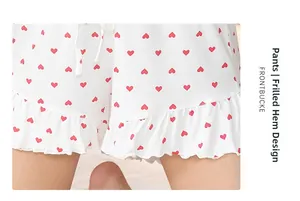 Detail of white pajamas shorts featuring red heart print and ruffled hem with drawstring