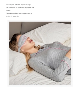 Détail d'un pyjama en modal avec liseré rose et masque de sommeil sur un lit blanc