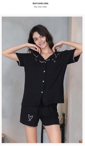 Détail d'un pyjama en modal noir avec bords à volants rose et broderie de cœur