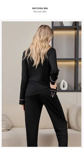 Détail d'un pyjama rayé noir avec liseré rose et broderie V sur la poche arrière