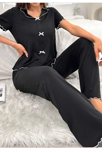 Détail du pyjama noir col en V avec bordures en dentelle blanche et petits nœuds décoratifs