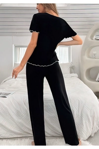 Vue arrière du pyjama en tricot noir avec bords ondulés blancs aux manches et à l'ourlet