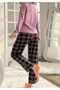 Detail von rosa geripptem Pyjama-Oberteil und karierter Hose an einem Model zu Hause