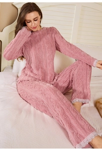 Detail of pink coral fleece pajamas set with cable knit texture and white lace trim