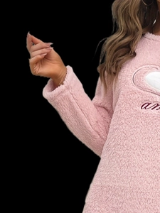 Détail d'un vêtement d'intérieur en polaire rose avec cœur blanc et broderie