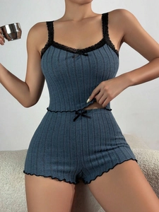 Detail of blue ribbed pajama set with black lace trim and bow accents on fabric