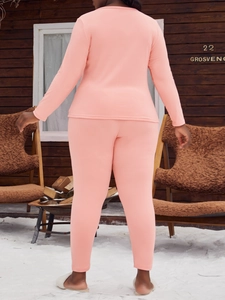 Ensemble pyjama thermique rose pour femme vue de dos dans un chalet d'hiver douillet