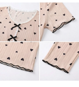 Detail of pink pajamas with black heart prints, lace V-neckline, and cute bow decoration