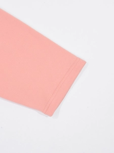 Détail d'une manche de pyjama rose clair avec double couture et texture en maille douce