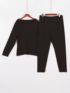 Présentation suspendue d'un pyjama noir uni à manches longues avec col rond et pantalon