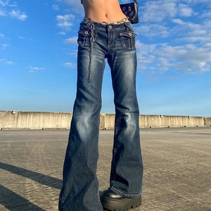 Detail of low-rise flared jeans in dark blue with side flap pockets and metal chain belt