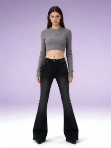 Détail d'un jean évasé noir à taille haute porté avec un haut gris à manches longues côtelé
