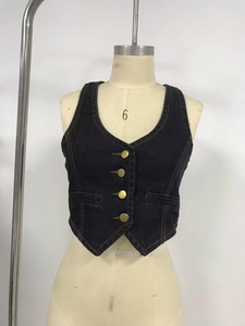 Détail d'un gilet en jean délavé foncé avec col en V et quatre boutons en métal doré