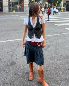 Style urbain avec un gilet en jean noir vintage associé à une chemise blanche à volants blanche