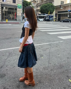 Détail d'une jupe plissée en jean bleu foncé avec un style urbain et des bottes en cuir
