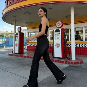 Close-up of black high-waist flared jeans and tank top in a vintage street setting