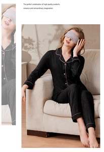 Detail of black ribbed knit pajamas with pink piping trim and a matching sleep mask