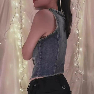 Side view of a vintage washed denim vest with structural stitching and cropped fit