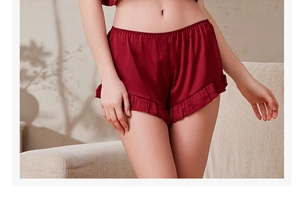 Dettaglio pantaloncini pigiama in raso rosso scuro con vita elastica e volant