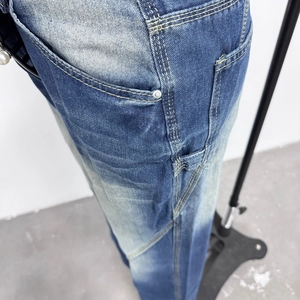 Detail of light blue washed denim jeans with yellow contrast stitching and metal rivets