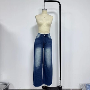 Detail view of high-waisted wide-leg denim jeans with vertical fading and frayed hems