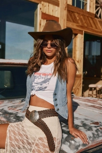 Détail d'un gilet en jean vintage avec jupe en dentelle blanche et chapeau de cowboy