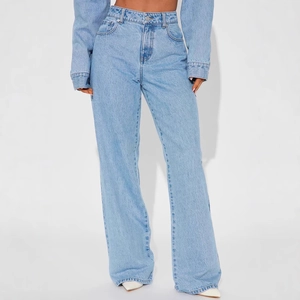 Détail du jean taille haute bleu clair avec bouton métallique et poches classiques