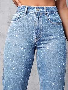 Dettaglio di strass argentati scintillanti su jeans celesti a vita alta trendy