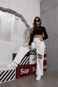 Detail of white high-waisted distressed wide-leg jeans with stylish knee cut-outs