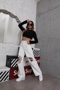 Detail view of white high-waisted distressed denim jeans with knee rips and straight cut