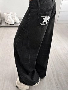 Detail of white star embroidery on the back pocket of washed black wide-leg jeans