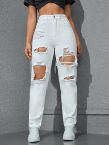 Detail shot of distressed white high-waisted jeans with large cutouts and frayed edges