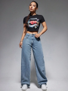 Détail d'un jean large taille haute bleu clair avec un crop top noir à motif fraise