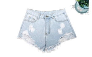 Flat lay detail of distressed light blue denim shorts with frayed hems and ripped texture